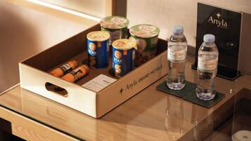 A minibar with a variety of beverages and snacks, including cans of Lay's chips, cans of Stax, and bottles of water.