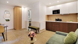 Een ruimtelijk ingerichte leefruimte met kitchenette, eethoek en zithoek.