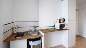 Une cuisine de taille réduite équipée d’un évier, d’une cuisinière, d’un four à micro-ondes et d’une poubelle.