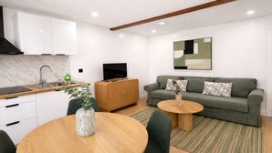 A modern living room with a sofa, a coffee table, a TV, and a kitchen area with a sink and cabinets. - Charmant appartement a Aubervilliers, 4 personnes (Aubervilliers)