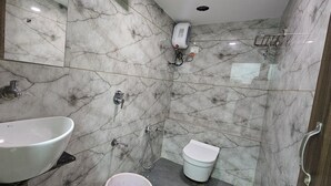 Un bagno con pavimento in marmo, lavandino bianco, toilette e doccia.