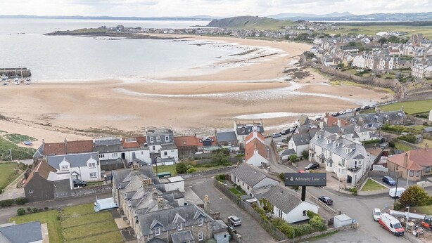 A coastal town with a sandy beach, residential buildings, and a sign for '4 Admiral Lane.' - Admiralty Lane (No 4) (Elie)