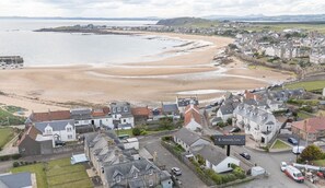A coastal town with a sandy beach, residential buildings, and a sign for '4 Admiral Lane.' - Admiralty Lane (No 4) (Elie)