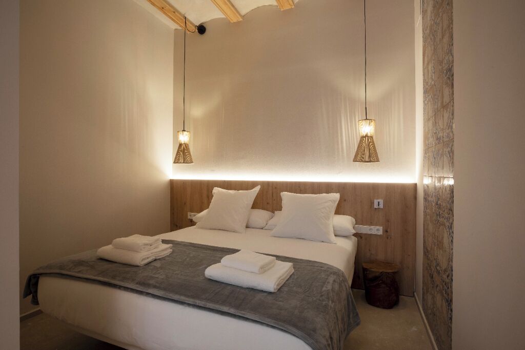 A modern hotel room with a large bed, two bedside tables, and a wooden headboard.