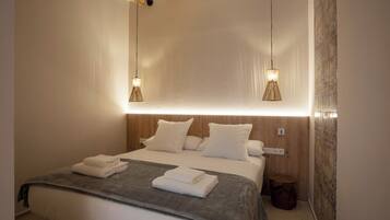 A modern hotel room with a large bed, two bedside tables, and a wooden headboard.