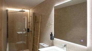 Un baño moderno con cabina de ducha de vidrio, inodoro, lavabo con espejo e iluminación empotrada en el techo.