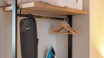 Ein kleines Zimmer mit Etagenbett, einem Schreibtisch inklusive Tastatur und einer Kleiderstange.