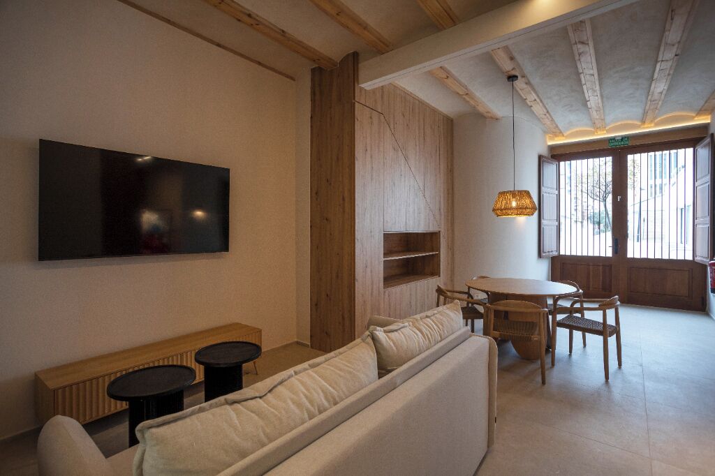 Une pièce confortable avec un canapé, une petite table et un téléviseur fixé au mur.