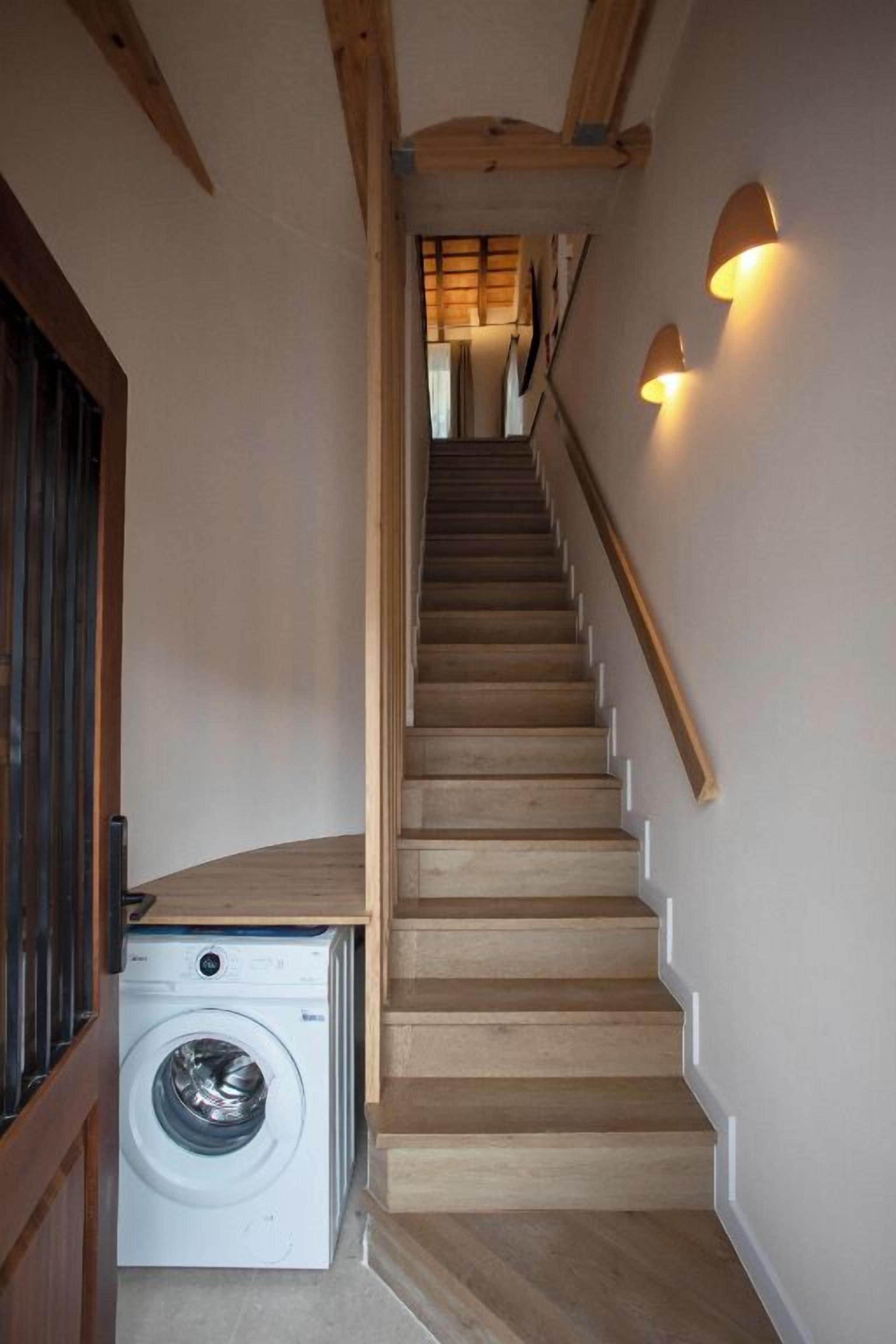A wooden staircase with a washing machine at the bottom.