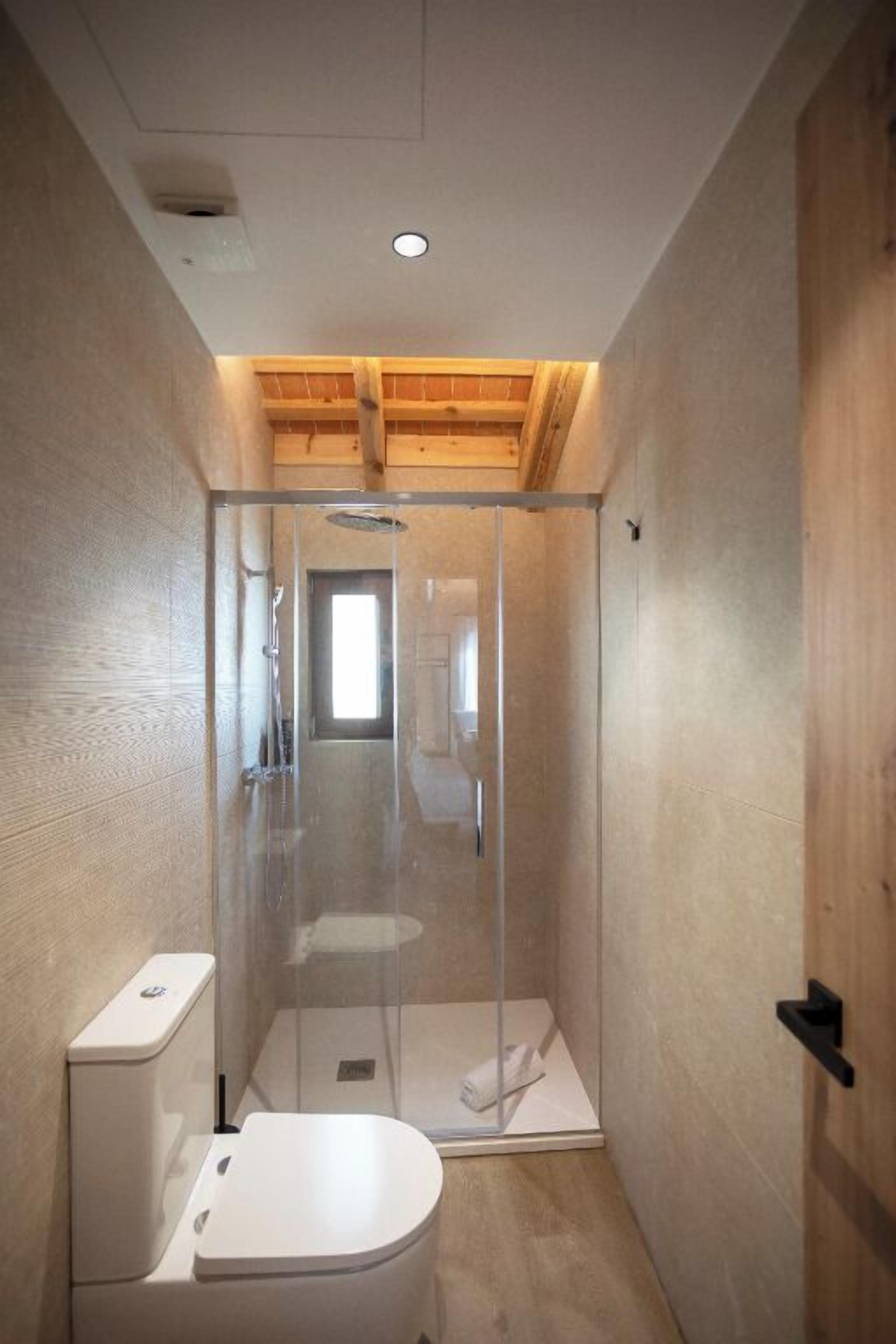 Une salle de bain moderne avec une douche à parois de verre, des toilettes et un plafond en bois.