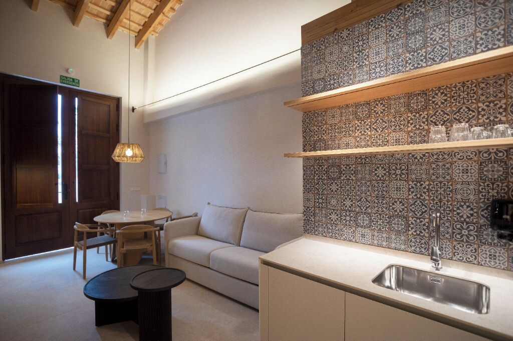 A compact kitchen with a sink, a round table, and a sofa.