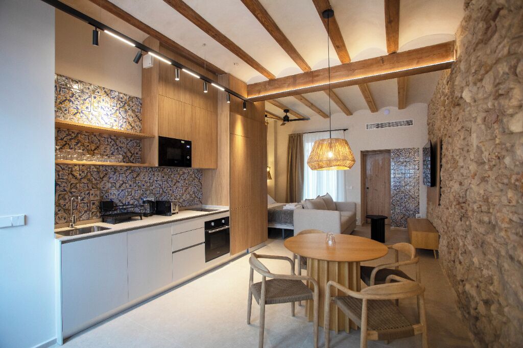Una cocina moderna con vigas de madera, una pared de piedra y un comedor con mesa y sillas redondas.