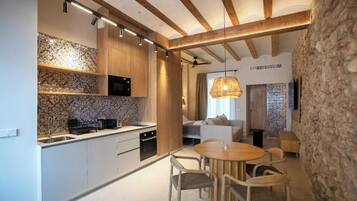 Una cocina moderna con vigas de madera, una pared de piedra y un comedor con mesa y sillas redondas.