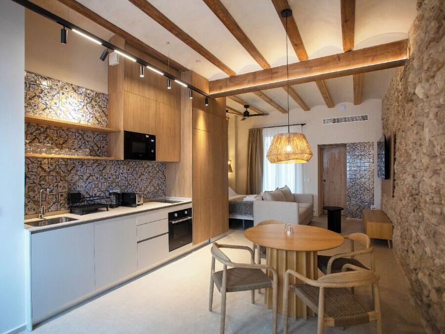 Una cocina moderna con vigas de madera, una pared de piedra y un comedor con mesa y sillas redondas.