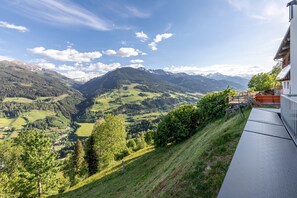A mountainous landscape with a view of a building with a balcony.