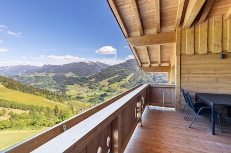 A wooden balcony with a view of a mountainous landscape.. Your Grubgut Getaway – Vacation with Mountain Views