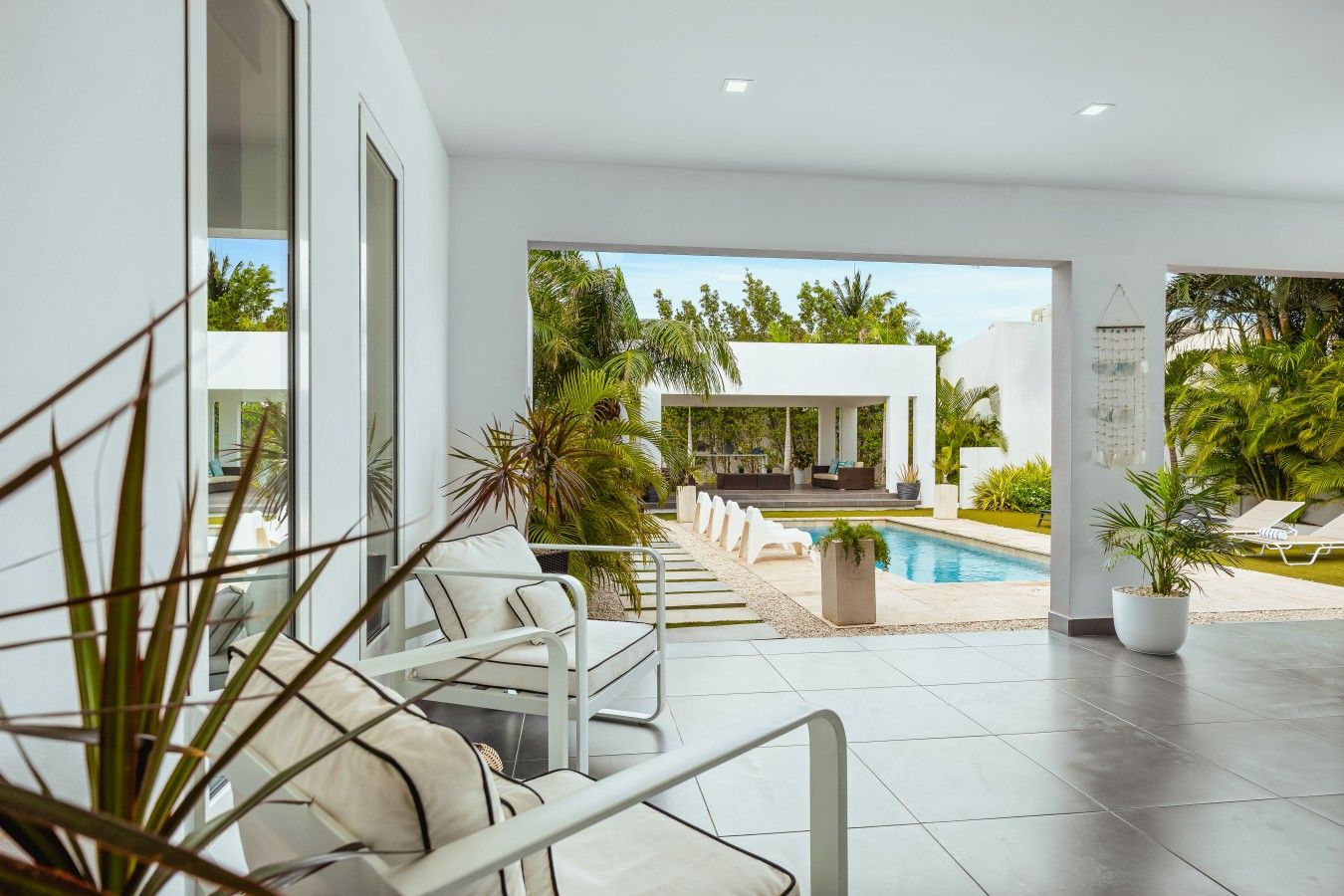 A modern indoor pool area with a clear view of the pool, lounge chairs, and a covered seating area.