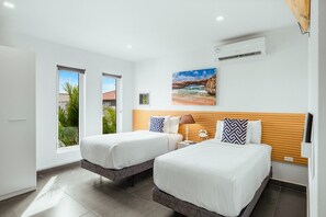 Une chambre d’hôtel avec deux lits, une fenêtre, un climatiseur et un tableau au mur.