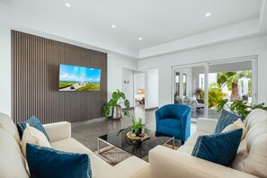 Un salon moderne doté d’un téléviseur à écran plat, de sièges confortables et offrant une vue sur l’extérieur.