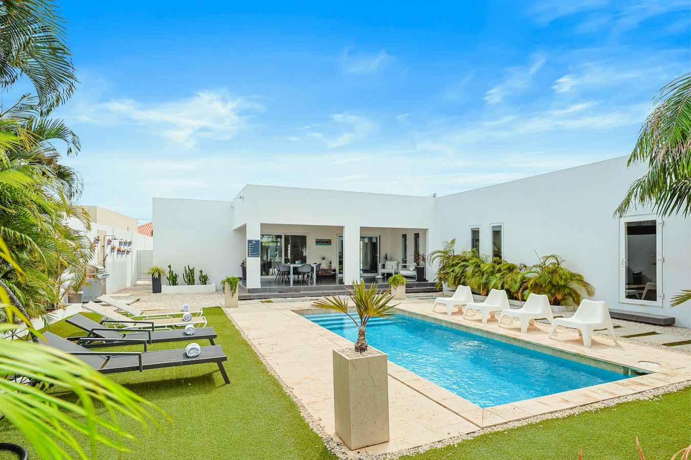 Et moderne hus med swimmingpool, udendørs møbler og en patio.