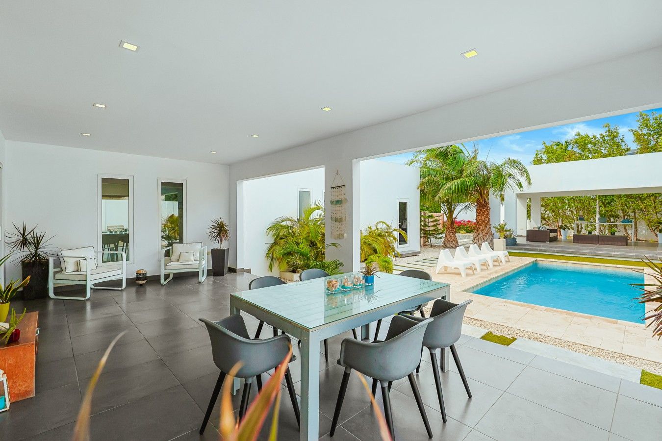 Un espace intérieur moderne doté d’une piscine, d’un coin salon et d’une table à manger.