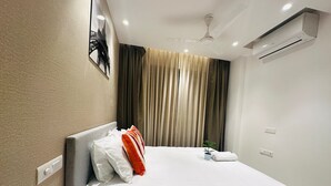A hotel room with a bed, a ceiling fan, an air conditioning unit, and a wall-mounted picture of the Eiffel Tower.
