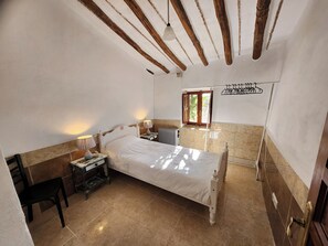 A bedroom with a bed, bedside tables, a radiator, and a window with a view of greenery. - Secluded Andalusian Casitas With Private Pool (Huercal-Overa)