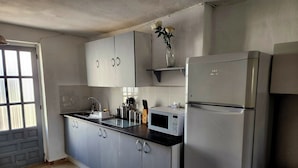 Une cuisine avec des meubles gris, un réfrigérateur en acier inoxydable, un four à micro-ondes et un évier.