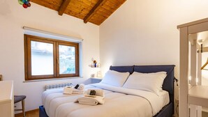 Quarto com cama, janela, mesa de cabeceira e guarda-roupa.