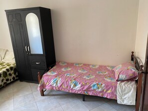 A bedroom with a bed, a wardrobe, and a chair.