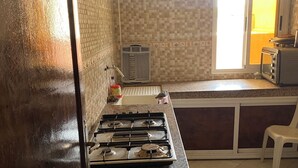 A kitchen with a gas stove, a microwave, and a toaster. There is a window with a view of the outside.