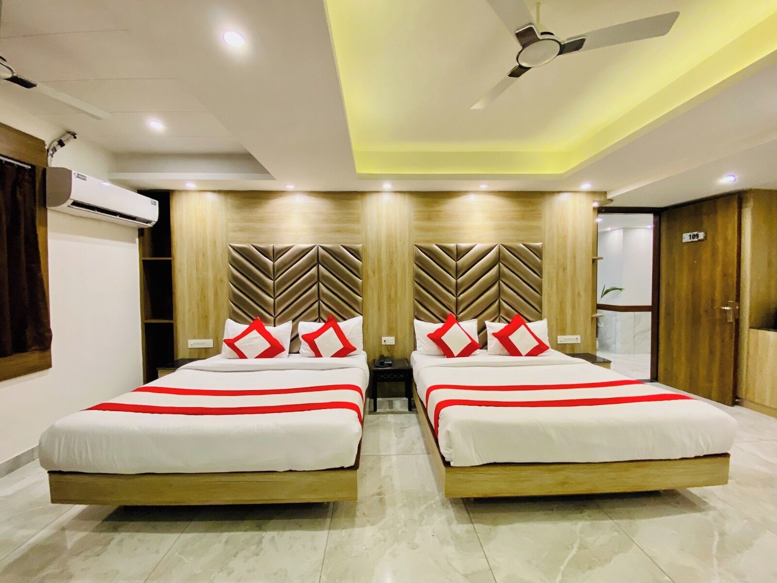 Habitación de hotel con dos camas, ventilador de techo y aire acondicionado.