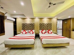 Habitación de hotel con dos camas, ventilador de techo y aire acondicionado.
