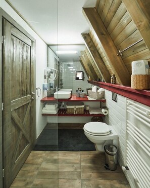 A compact bathroom with a wooden door, a white toilet, a sink with a red countertop, and a mirror. - Hai la Munte Bran (Bran)