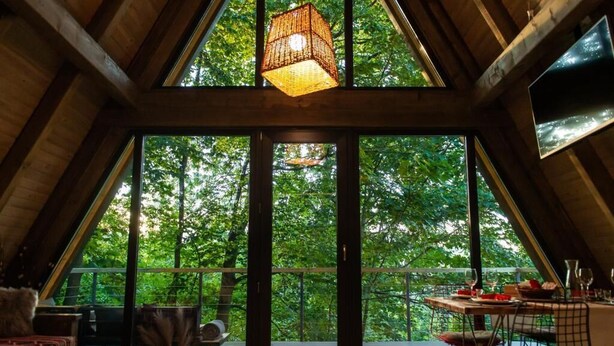 Ein geräumiges Zimmer mit großen Fenstern, einer Holzbalkendecke und einer Hängeleuchte.