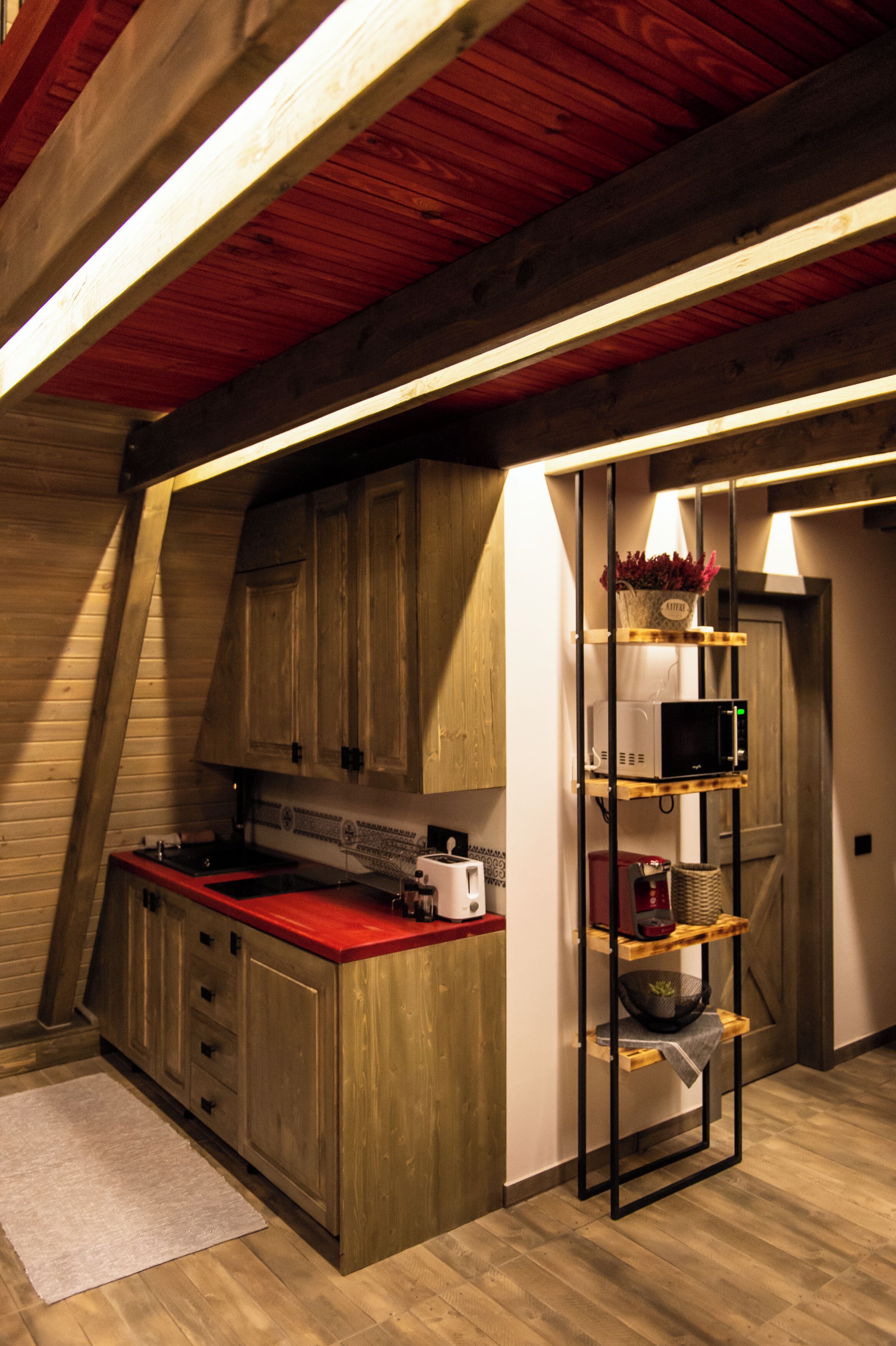 A kitchen with wooden cabinets, a red countertop, and a microwave.