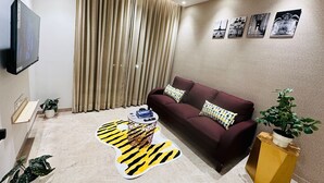 Een woonkamer met een bank, een salontafel, een televisie en een muur met ingelijste foto's.