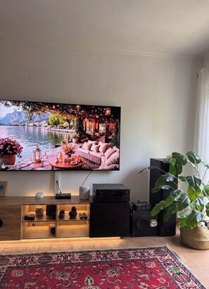 A living room with a flat-screen TV, a sofa, a coffee table, and a red patterned rug. - Modern villa with AC in Lougratte (Lougratte)