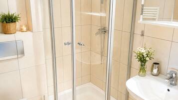 A modern bathroom with a glass-enclosed shower, a white sink, and a toilet.