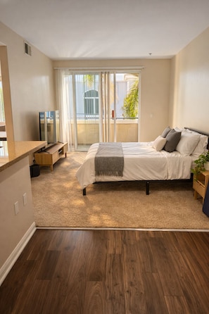 Ein Schlafzimmer mit Bett, Fernseher, Schreibtisch und einem Balkon mit Blick.