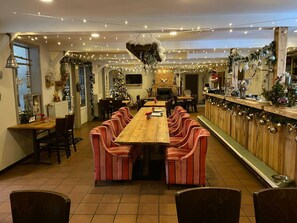 A long wooden dining table with striped chairs, a fireplace, and Christmas decorations.