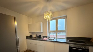 Una cocina moderna con un refrigerador de acero inoxidable, un horno empotrado, un microondas, un lavamanos y un ventanal con vistas al exterior.