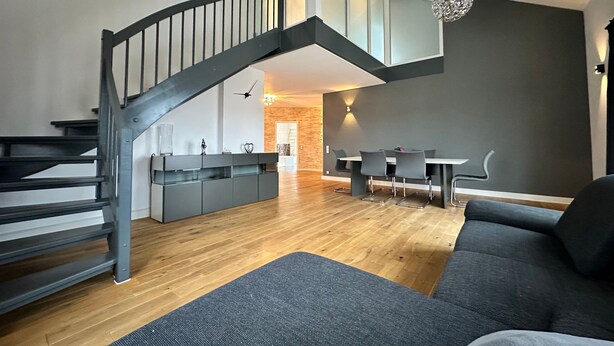Un espacio moderno para vivir con escalera, comedor y sofá.
