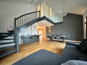 A modern living space with a staircase, a dining area, and a sofa. - Apartment in A Hotel 'Penthouse Gersthofen' with Mountain View, Private Terrace and Wi-Fi (Gersthofen)