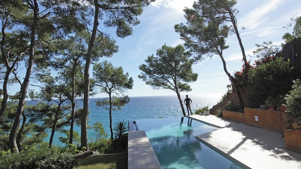 A swimming pool with a view of the sea, surrounded by trees and a wooden deck. - Luxury Seafront Villa • Infinity Pool - Walk to Beach (Tarragona)
