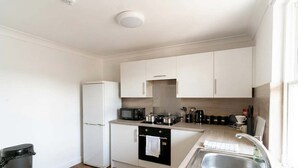 Una cucina compatta con mobili bianchi, un forno a microonde, un piano cottura e un lavello.