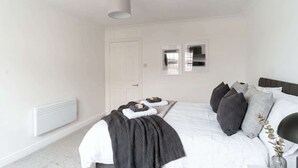 Una camera da letto con un letto, un termosifone, una porta e un punto luce a parete.