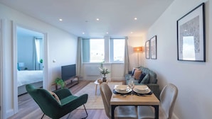 A modern living room with a dining area, a sofa, and a TV. - Fabulous 1 Bedroom Apartment in Gravesend Centre (Gravesend)