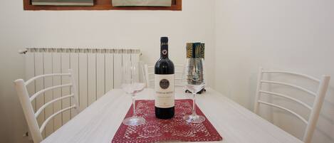 A dining table with a bottle of wine, two wine glasses, and a decorative item on a red placemat.