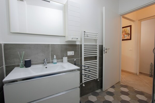 Een badkamer met een witte wastafel, een handdoekhouder en een spiegel.